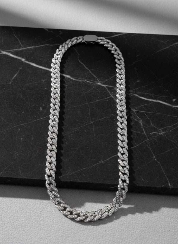 Chaîne Ambition 12 mm AJ&Co, finition argentée, chaîne à zircons présentée sur un support en marbre.